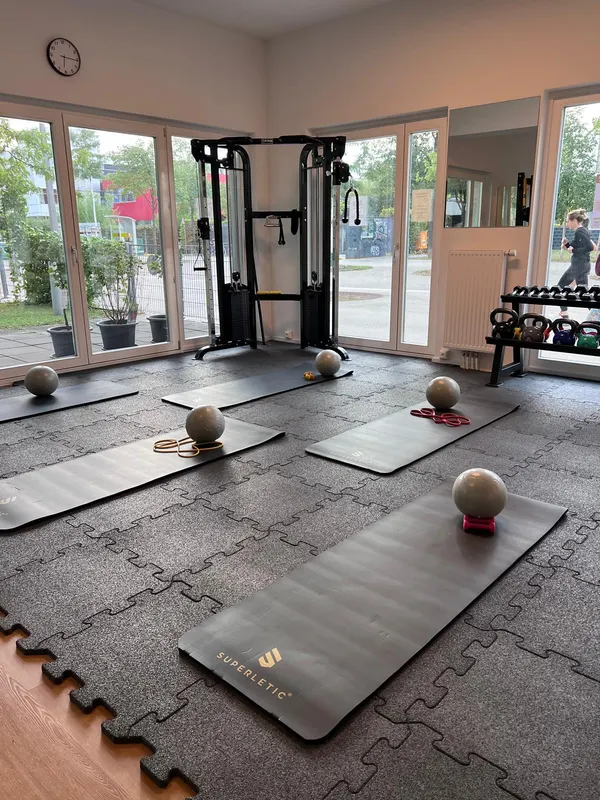 Vorbereitete Trainingsmatten mit Bällen und Bändern vor großen Fenstern
