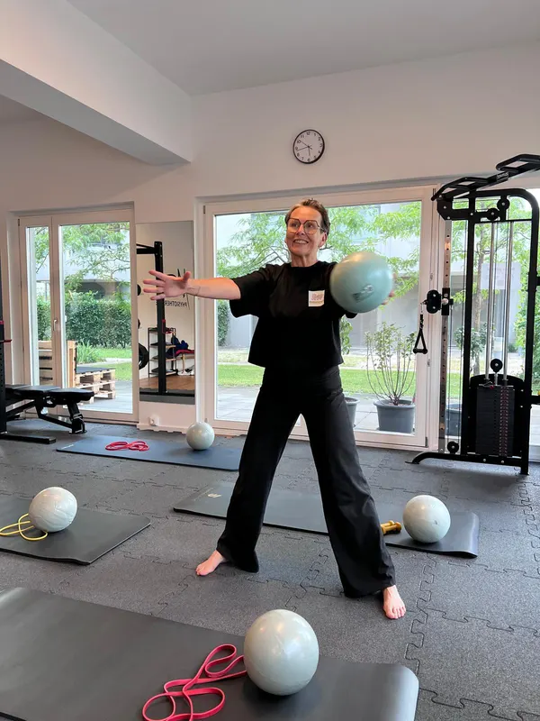 Tini schwingt lachend einen Ball zur Seite